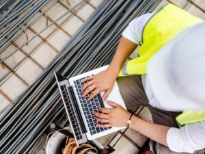 a man using technology (a laptop) on a construction site